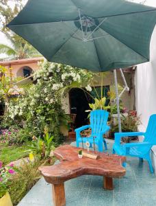 阿约拉港Nelyza's Suites & Adventure的一张桌子和两把椅子以及一把绿色雨伞