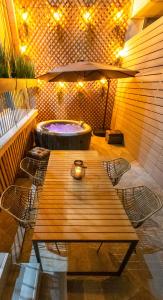纳弗帕克托斯Lepanto Luxury Apartments GF的庭院配有木桌和椅子,设有热水浴池