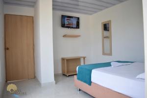圣玛尔塔Hotel Perla del Caribe的卧室配有一张床,墙上配有电视。