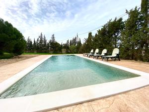 奇克拉纳－德拉弗龙特拉Agradable casa de campo con piscina en la Barrosa的一个带三把椅子的游泳池和一个泳池景泳池