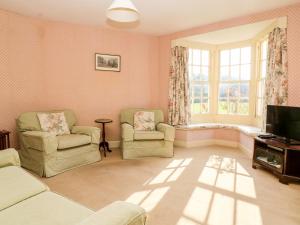 BoyntonCarr Cottage的客厅配有两把椅子和电视