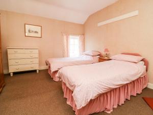 BoyntonCarr Cottage的一间卧室设有两张床、一个梳妆台和窗户。