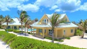 Brinkleys海洋天堂酒店的棕榈树海滩上的黄色房子