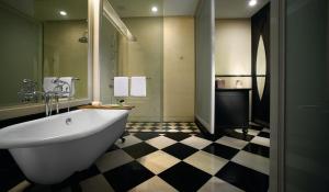 乔治市依恩奥酒店的一间带白色浴缸和 ⁇ 格地板的浴室