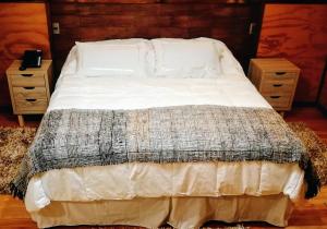 达卡卫Hotel Aliwen的卧室内的一张带白色床单和枕头的床