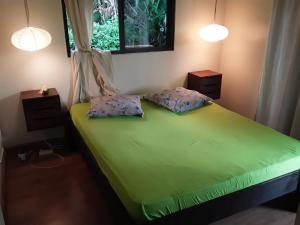 帕皮提ROYAL VAI的一间卧室配有带两个枕头的绿色床