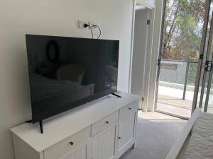 黄金海岸Superstar’s home stay的客厅的白色橱柜上配有平面电视