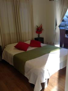 帕皮提ROYAL HERE的一间卧室配有一张带红色和绿色枕头的大床