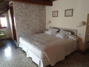 FortiáCan Bayre-Casa Rural的一间卧室设有一张带石墙的大床