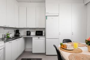 波里Apartments Borg Wellamo的厨房配有白色橱柜和一张带一碗水果的桌子