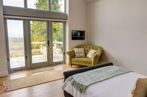 切尔滕纳姆Cheltenham View Lodge的一间卧室配有床、椅子和滑动玻璃门