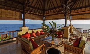 艾湄湾峇都汤加别墅酒店的一个带沙发和椅子的门廊,享有海景