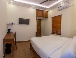 特里凡得琅Ekana Homes的卧室配有一张床,墙上配有电视