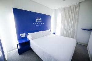 莱昂阿尔班尼旅馆的卧室配有白色的床和蓝色的墙壁