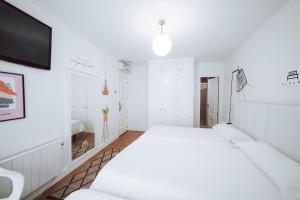 莱昂Hostal Misericordia的一间白色卧室,配有床和电视