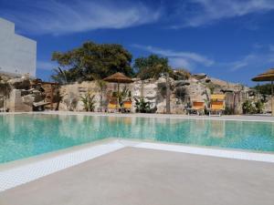 法维尼亚纳洛亚希艾尔伯格乡村酒店的度假村的游泳池,配有椅子和遮阳伞