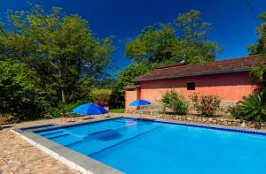 伊波兰加Pousada Casa de Pedra的一座游泳池,旁边设有两把遮阳伞