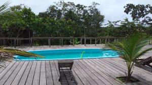 CareiroAmazon Boto Lodge Hotel的一个带椅子的木甲板上的游泳池