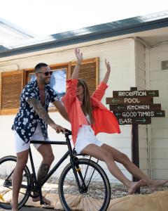 黄金海岸冲浪者背包客巴兹旅舍的男人和女人骑着自行车,手臂在空中
