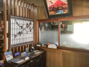 富士河口湖柏屋旅馆的配有一张桌子、一个窗口和一个显示器的房间