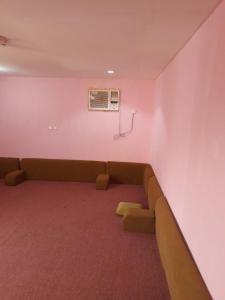穆哈伊犁Alkithri Apartments for Singls的一间位于粉红色房间中的沙发等候室