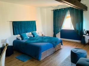蒙托邦Manoir de la Gravette Maison d'Hôtes的一间卧室配有一张带蓝色床单的床和一扇窗户。