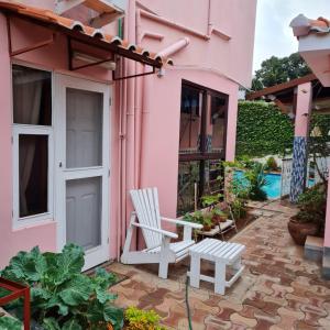 马普托Casa Quimera的粉红色的房子,配有椅子和长凳