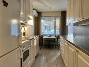 于韦斯屈莱Time Apartments Kärpänkuja的厨房配有白色橱柜、桌子和窗户。