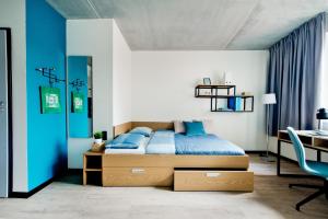 格但斯克MILESTONE Gdańsk Center的一间卧室设有蓝色的墙壁、一张床和一张书桌