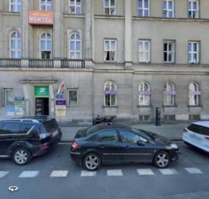 华沙Oliwka Hostel的两辆汽车停在大楼前的停车场