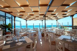 库基尼坎尼奥Themis Beach Hotel的餐厅设有桌椅,以大海为背景