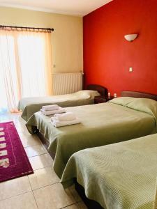 纳乌萨玛西亚斯阿斯特拉斯酒店 的一间设有三张床和红色墙壁的房间