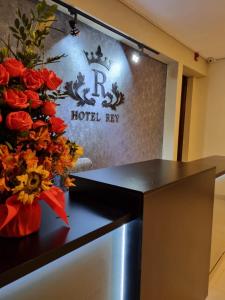 万卡约Hotel Rey的一间酒店客房,桌子上摆放着标志和鲜花
