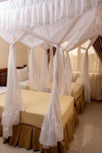 阿鲁沙Briston Hotel的白色窗帘的房间的一排床
