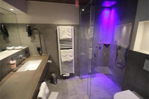 瓦尔茨胡特田根Genuss- und Wellnesshotel Bercher的带淋浴的浴室(带紫色照明)