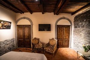 维泰博Il giardino nel borgo的卧室配有两把椅子和墙上的电视。