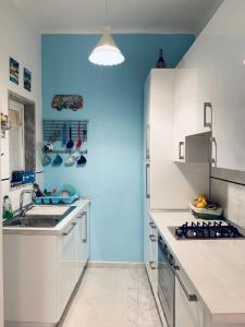 韦内雷港Appartamento SoloSoleMare的厨房配有白色橱柜和蓝色的墙壁