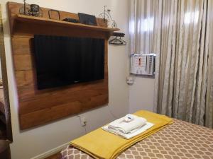 维多利亚ACONCHEGANTE QUARTO - PRAIA do CANTO的一间卧室配有一张床和一台平面电视