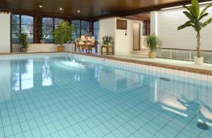 阿尔戈伊地区伊斯尼林德霍厄酒店的一座大型游泳池,其中两人坐在桌子上