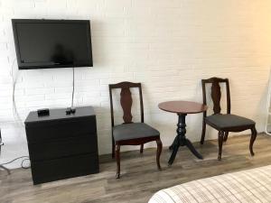 奥里利亚湖滨酒店的一间设有两把椅子、一张桌子和一台电视的房间