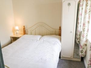 Carrowsallagh BridgeThe Cottage的卧室配有白色的床和边桌