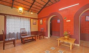 马迪凯里Itsy By Treebo - Allaranda Homestay With Valley View的一间设有桌椅和红色墙壁的房间