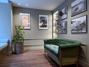 萨拉戈萨AZ Hotel San Valero的客厅配有绿色沙发和墙上的照片