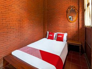 TrowulanOYO Homes 90948 Desa Wisata Kampung Majapahit的砖墙房间的一个床位