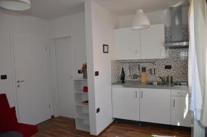 科佩尔Apartments Bertok的厨房配有白色橱柜和红色椅子
