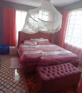 EmbuMegs Place - Red - Embu Town的一间卧室配有一张粉红色的床和天蓬