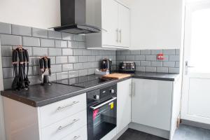 布莱克浦Withnell Stays - Apartment One - Ground Floor的厨房配有白色橱柜和黑色台面