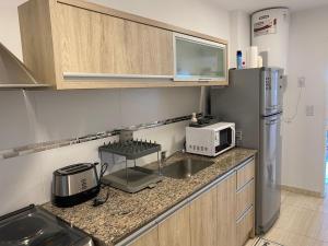 西波列蒂Departamento Nuevo en Cipolletti的厨房配有水槽、微波炉和冰箱