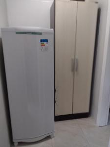 格拉玛多Kitnet Namorados的两个橱柜旁边的房间里装有白色冰箱