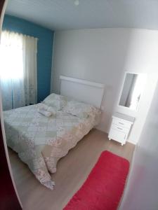 格拉玛多Kitnet Namorados的一间卧室配有床、镜子和红色地毯